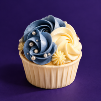 Denim Ruffle cupcake with a blue rosette beside a cream rosette, finished with sugar pearls