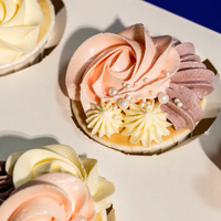 Close-up of a Blush Rosette cupcake: peach rosette, mauve petals, cream stars and sugar pearls