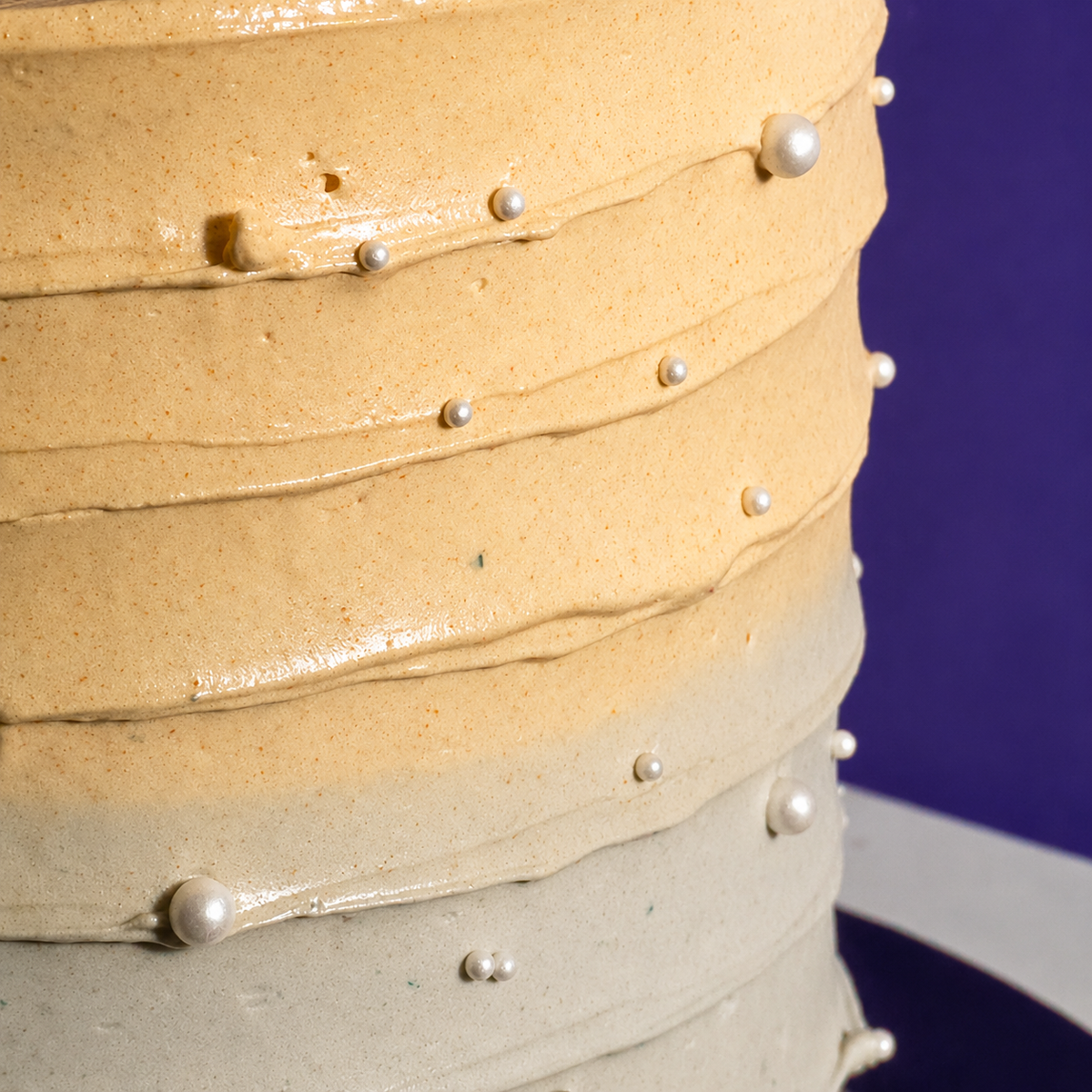 Close-up of the ridged pale gold and grey ombré buttercream and sugar pearls