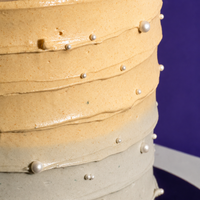 Close-up of the ridged pale gold and grey ombré buttercream and sugar pearls