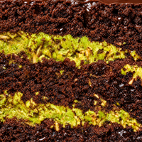 Close-up of pistachio cream and kataifi pastry between dark chocolate sponge layers