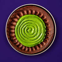 Top view of a pistachio cream swirl ringed with piped chocolate ganache