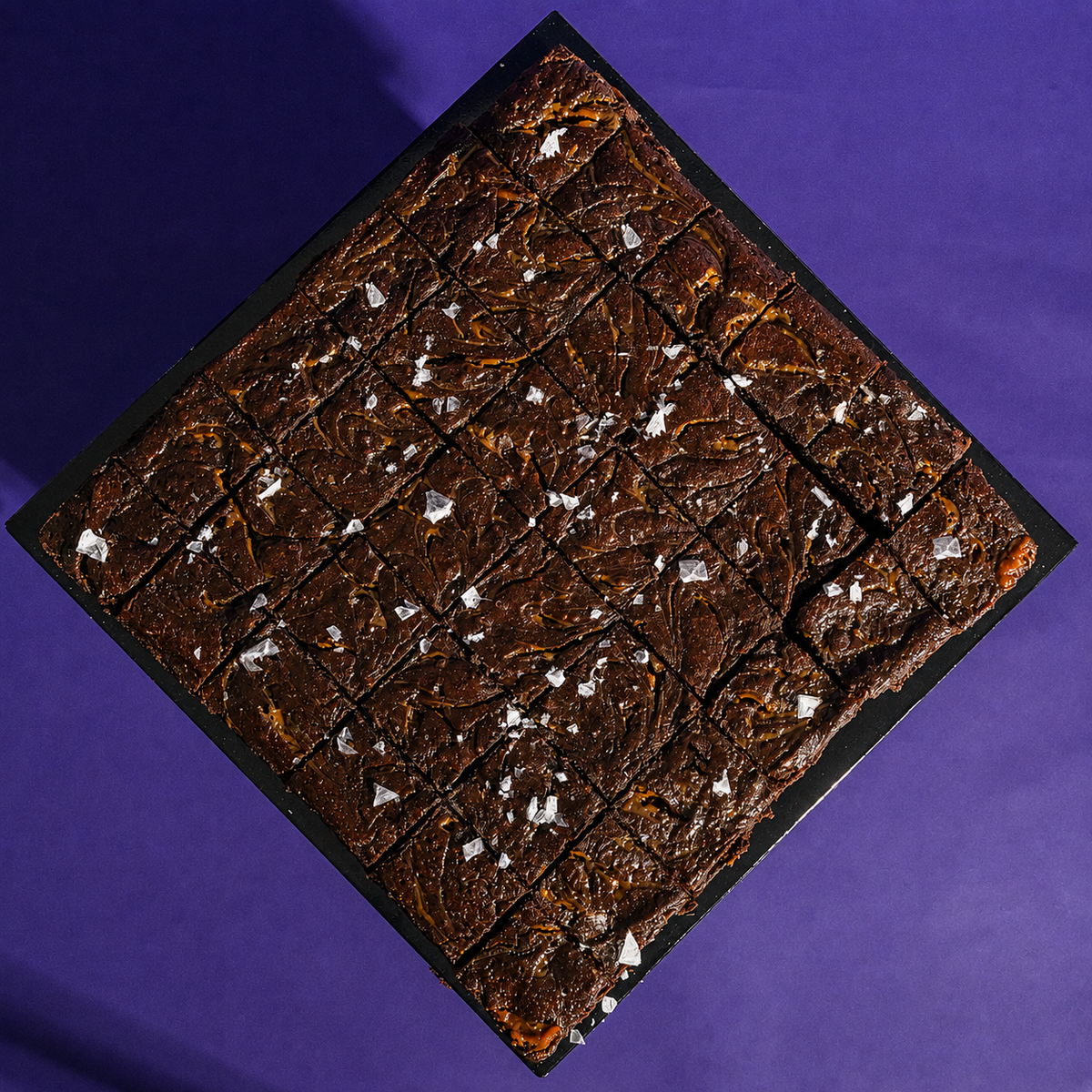 Sourdough salted caramel brownies pre-cut into 36 squares on a black board, ready to share