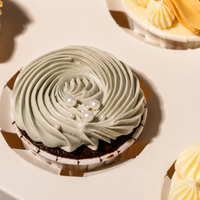 Top-down close-up of a Sunny Swirl chocolate cupcake with a pale sage swirl and white sugar pearls