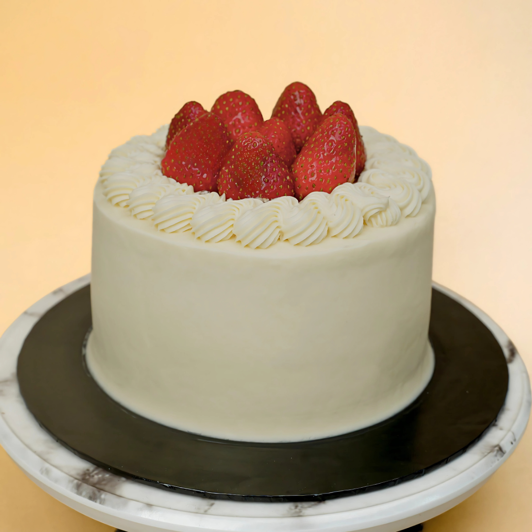 White cake with strawberries on a marble stand against a beige background