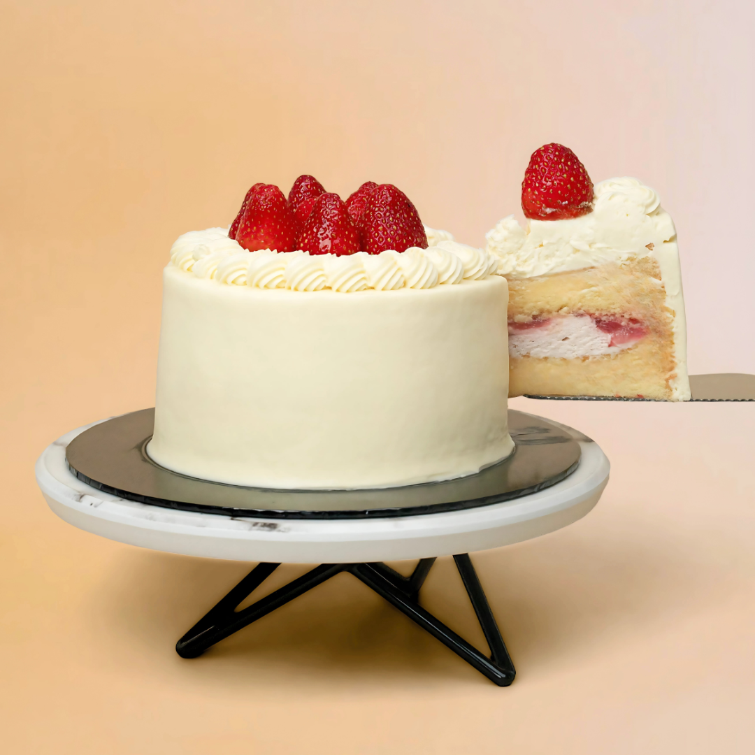 White cake with strawberries on a stand against a beige background