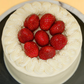 Cake with white frosting and red strawberries on a black plate