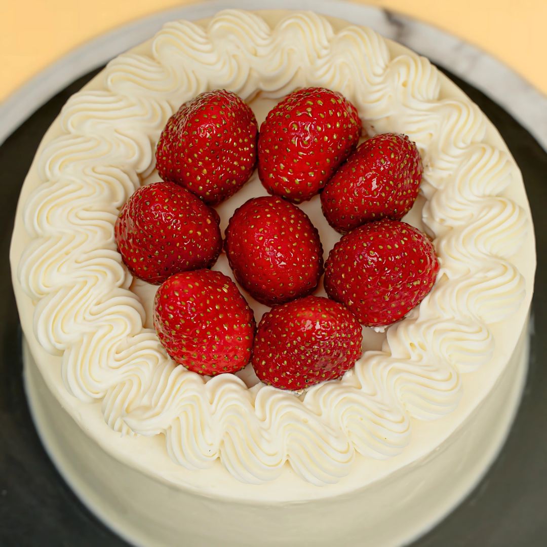 Cake with white frosting and red strawberries on a black plate