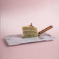 A Serving Slice of Side View of Lemon Poppyseed cake decorated with poppyseed, dehydrated lemon & rose petals on top by Elevete Patisserie