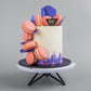 Side view of Clingy Macaron cake by Elevete Patisserie, 8 pieces of macarons clinging on to the side of a tall cake