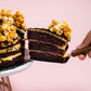Serving a slice of Salted Caramel Chocolate 9 Inch Cake with Popcorns on Top by Elevete Patisserie